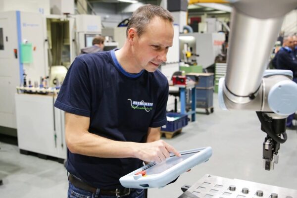 Mann bedient ein Tablet neben einem Cobot