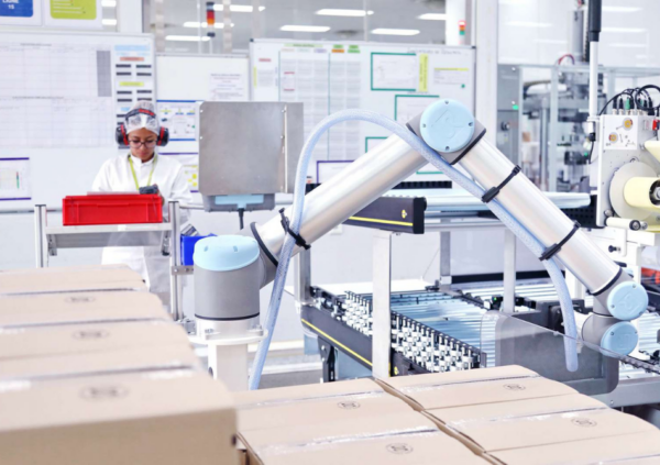 Mann mit Schutzbrille neben einem Cobot