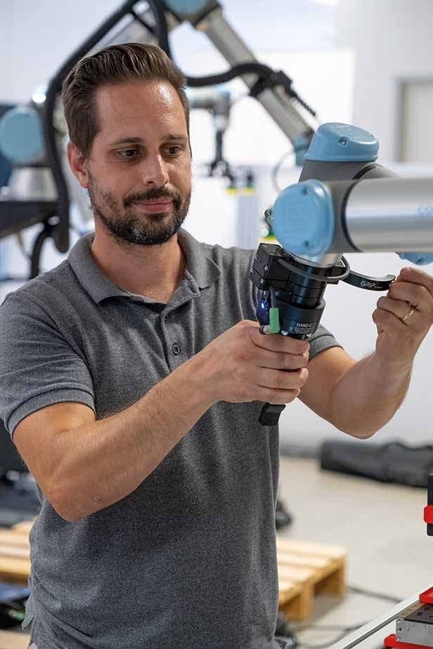 Mann befestigt Greifer an einem Cobot